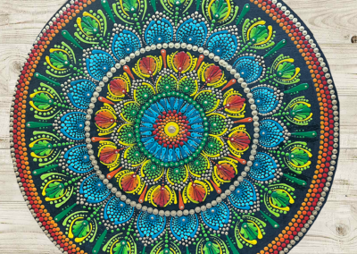 Sixteen inch board with mandala designs in blues, oranges, and greens.